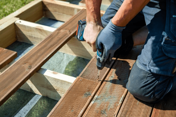 Deck construction builder hand with electric screwdriver installing impregnated wooden boards (1) Deck construction builder hand with electric screwdriver installing impregnated wooden boards